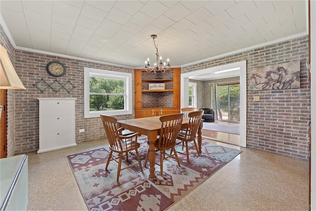 dining area with brick wall, an inviting chandelier, and crown molding