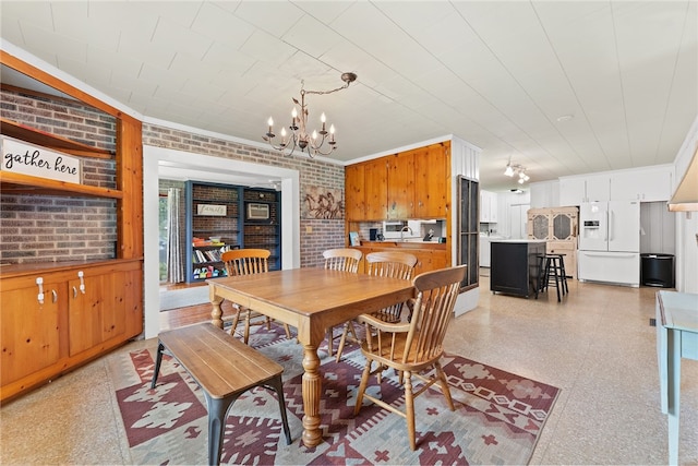 dining area featuring an inviting chandelier and brick wall