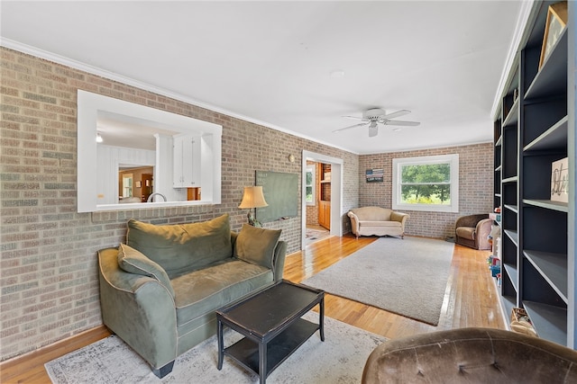 living room featuring brick wall, crown molding, hardwood / wood-style floors, and ceiling fan