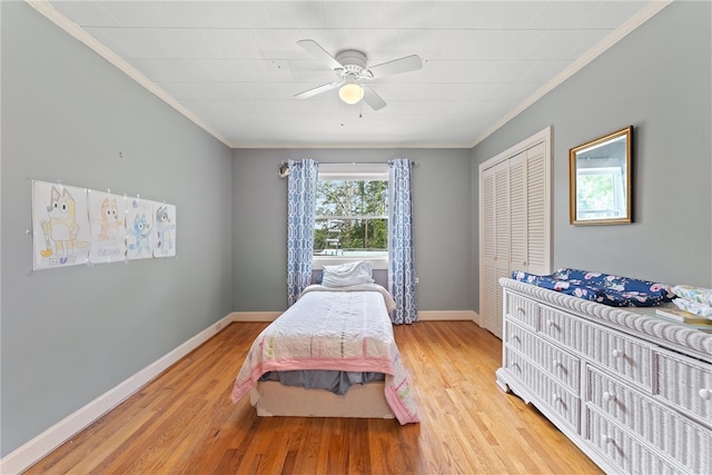 bedroom featuring light wood-type flooring, ornamental molding, ceiling fan, and a closet