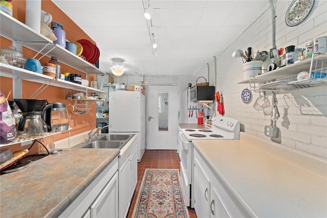 kitchen featuring white appliances, white cabinetry, dark tile patterned flooring, and brick wall