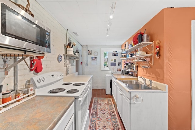 kitchen featuring sink, dark tile patterned floors, brick wall, white cabinetry, and white electric stove