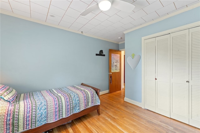 bedroom with a closet, ceiling fan, hardwood / wood-style flooring, and crown molding