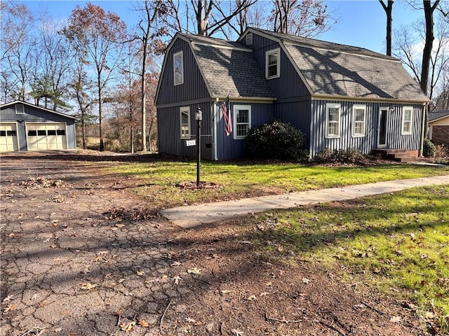 view of side of home featuring a garage, an outdoor structure, and a lawn