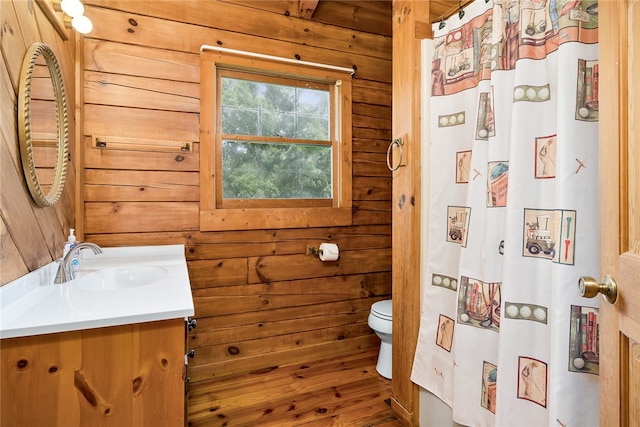 bathroom featuring water heater, wood walls, vanity, wood-type flooring, and toilet