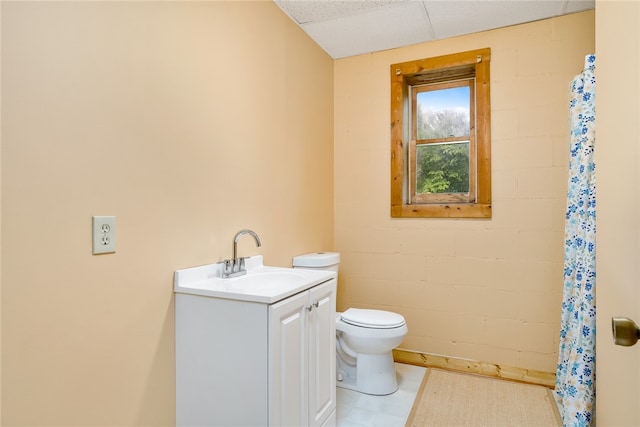 bathroom featuring a drop ceiling, walk in shower, vanity, and toilet