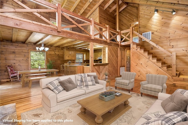 living room featuring an inviting chandelier, wood ceiling, wood walls, and light hardwood / wood-style floors