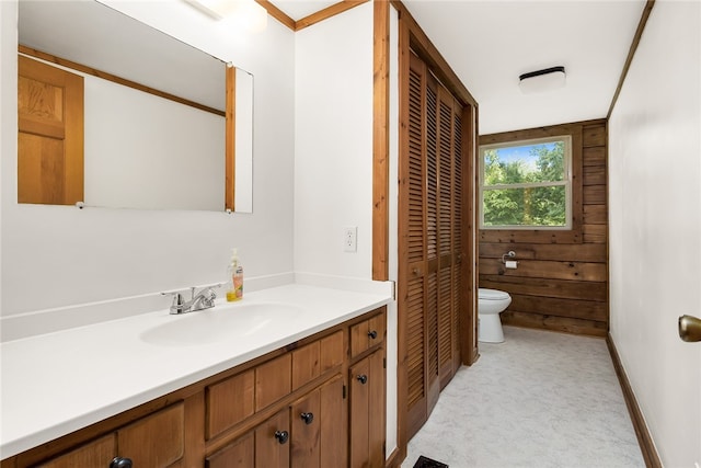 bathroom with wood walls, vanity, and toilet