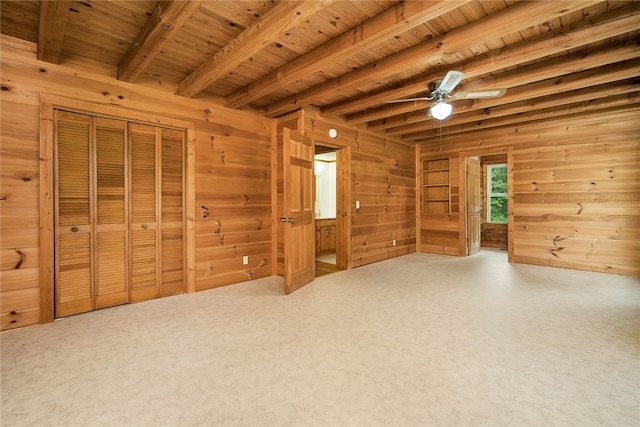 interior space featuring wooden walls, beamed ceiling, wooden ceiling, and carpet flooring