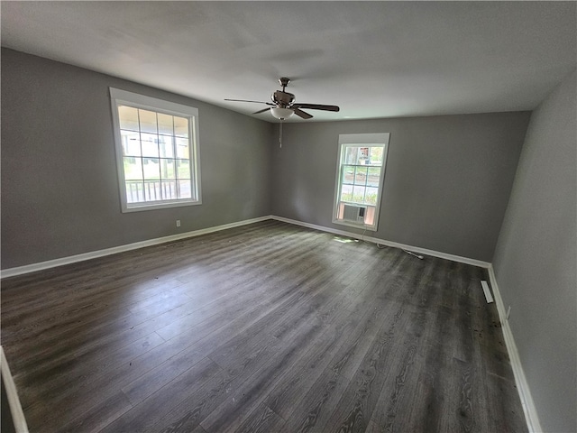 empty room with a healthy amount of sunlight, ceiling fan, dark wood-type flooring, and cooling unit