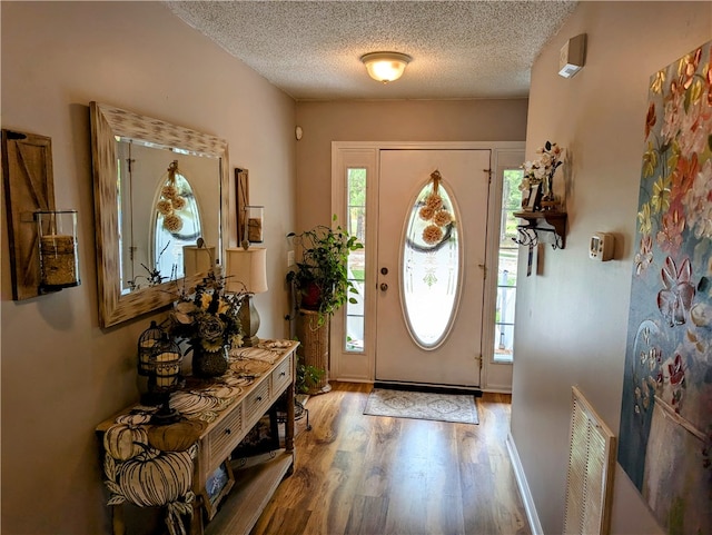 entryway with a textured ceiling, hardwood / wood-style flooring, and a wealth of natural light