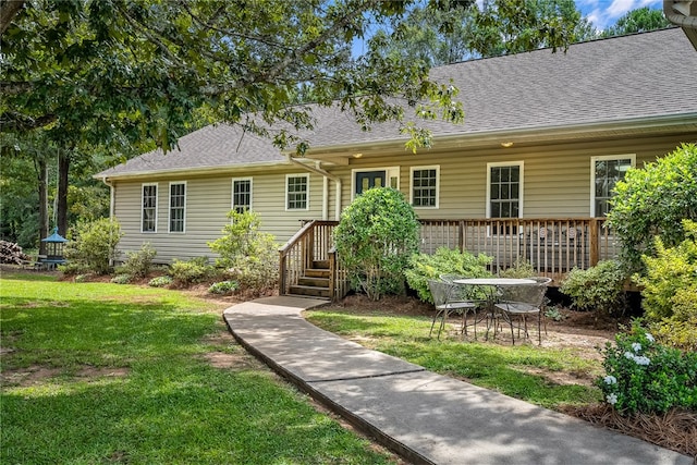 rear view of house with roof with shingles and a lawn