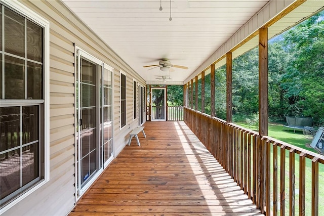 wooden deck featuring ceiling fan, a trampoline, and covered porch