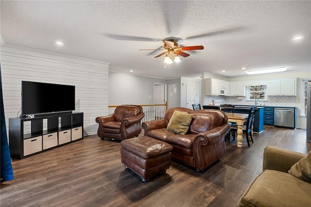 living room with a textured ceiling, ceiling fan, dark wood-style flooring, and crown molding