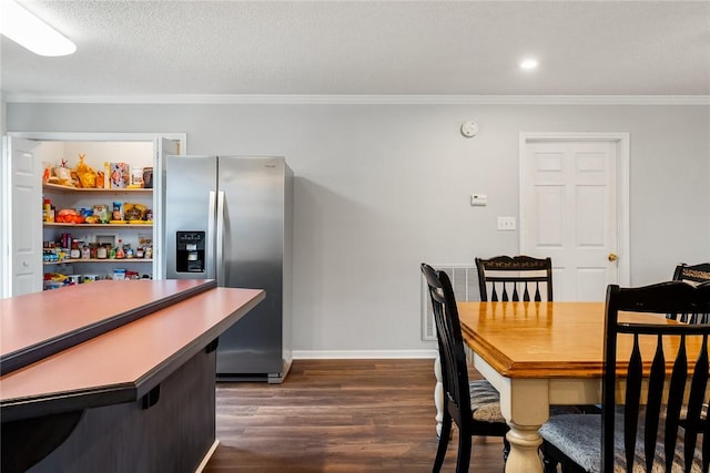 dining space with a textured ceiling, dark wood-type flooring, baseboards, and crown molding