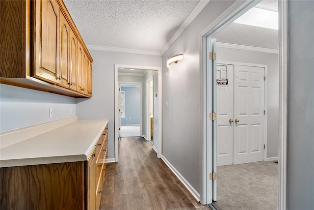 hallway featuring dark wood-style floors, crown molding, a textured ceiling, and baseboards