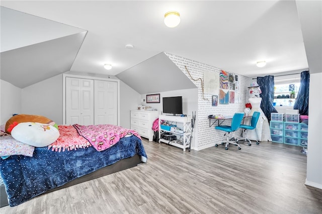 bedroom featuring wood-type flooring, a closet, and vaulted ceiling