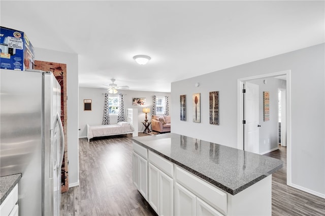 kitchen featuring dark stone countertops, white refrigerator with ice dispenser, dark hardwood / wood-style flooring, and white cabinetry