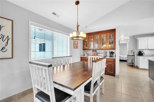 dining space featuring vaulted ceiling, light tile patterned floors, and a notable chandelier