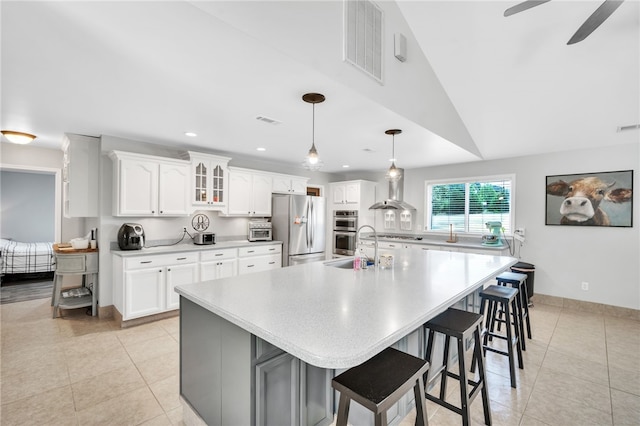 kitchen featuring a large island, stainless steel appliances, vaulted ceiling, and white cabinetry