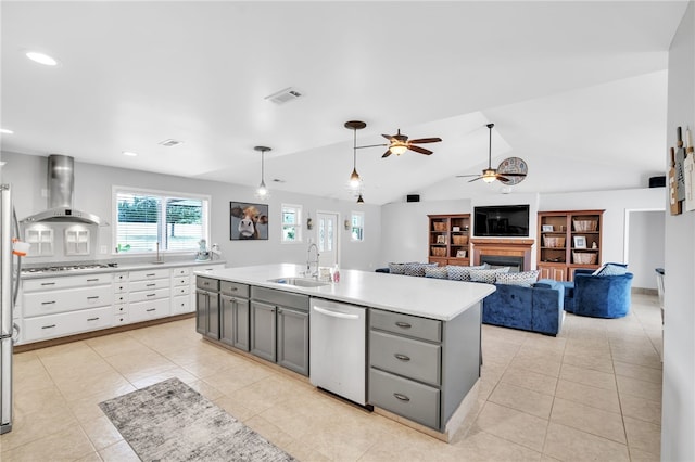 kitchen featuring vaulted ceiling, white cabinets, wall chimney exhaust hood, stainless steel appliances, and sink