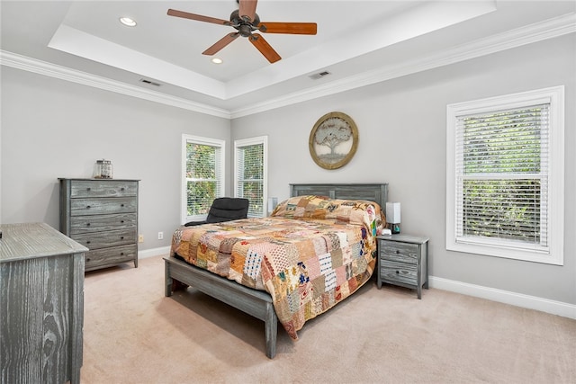 carpeted bedroom with ceiling fan, a raised ceiling, and ornamental molding