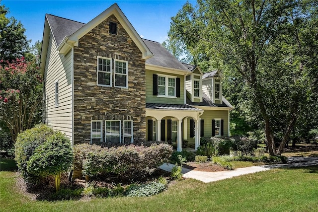 view of front of home featuring stone siding, covered porch, and a front yard