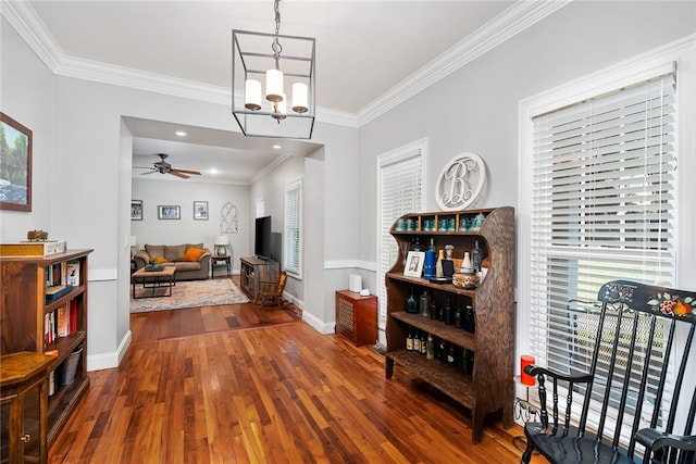 interior space with crown molding, a healthy amount of sunlight, ceiling fan with notable chandelier, and dark hardwood / wood-style floors