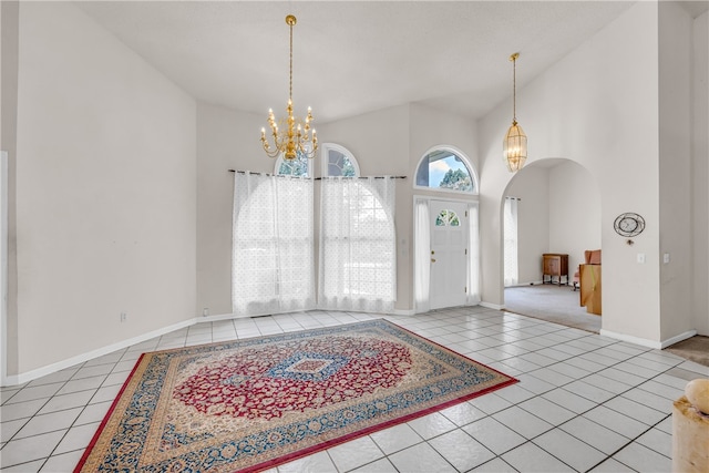 tiled entrance foyer featuring a towering ceiling and a chandelier