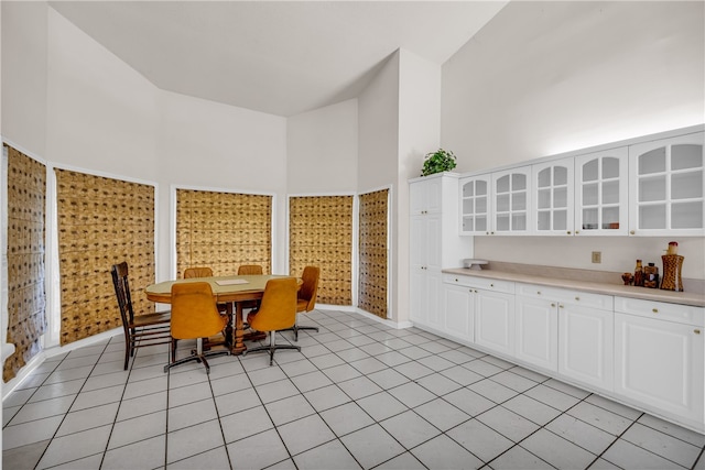 dining space featuring light tile patterned flooring and a towering ceiling