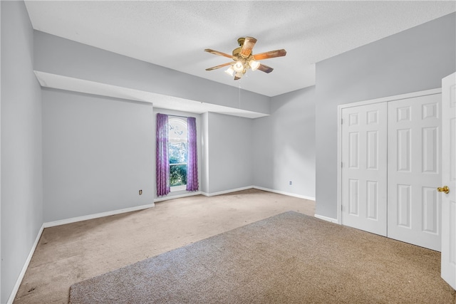 carpeted empty room featuring ceiling fan and a textured ceiling