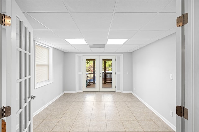 unfurnished room featuring a drop ceiling, light tile patterned flooring, and french doors