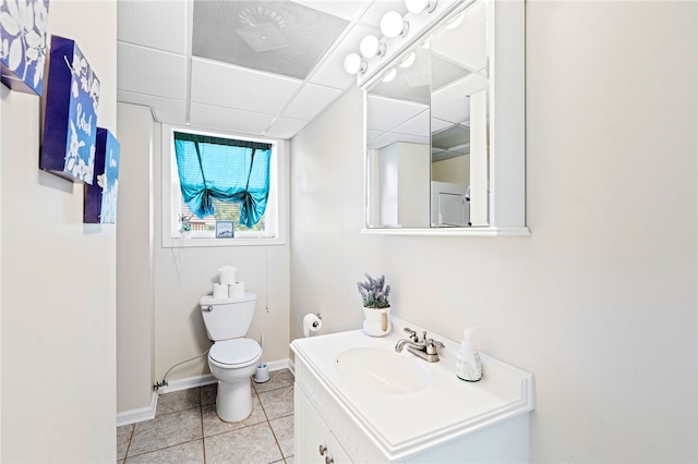 bathroom with tile patterned flooring, a paneled ceiling, vanity, and toilet