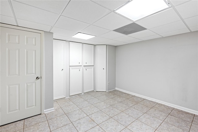 unfurnished bedroom with a drop ceiling, a closet, and light tile patterned flooring