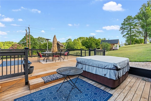 deck featuring a covered hot tub and a yard