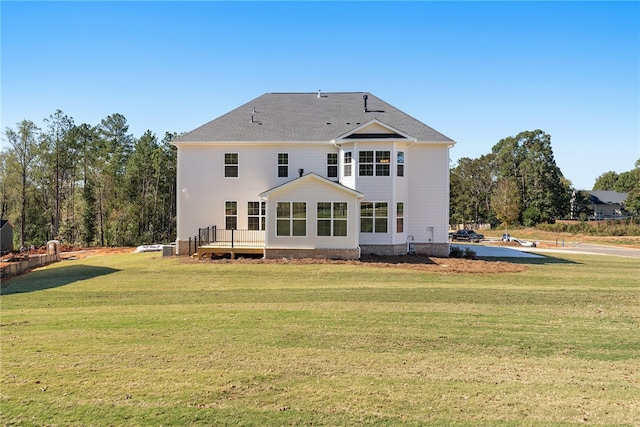 rear view of house featuring a wooden deck and a yard