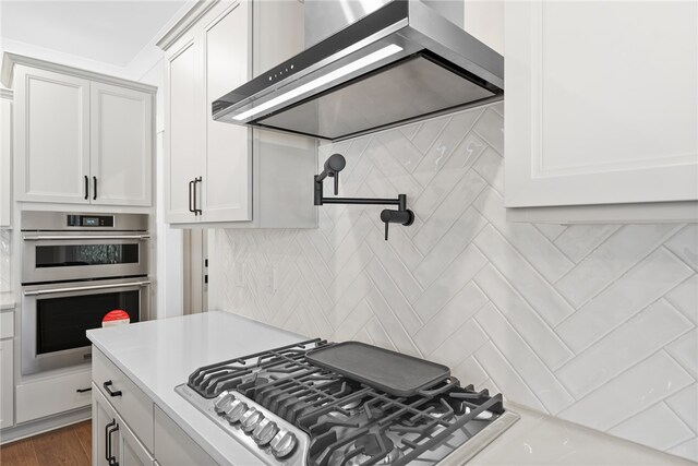 kitchen featuring appliances with stainless steel finishes, wall chimney exhaust hood, dark hardwood / wood-style floors, and white cabinets