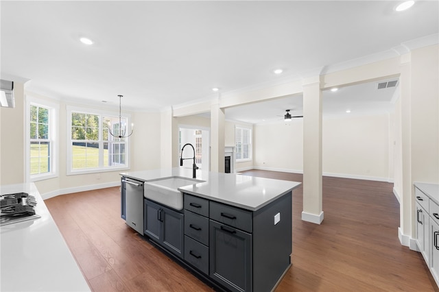 kitchen with appliances with stainless steel finishes, sink, an island with sink, ceiling fan with notable chandelier, and dark hardwood / wood-style flooring