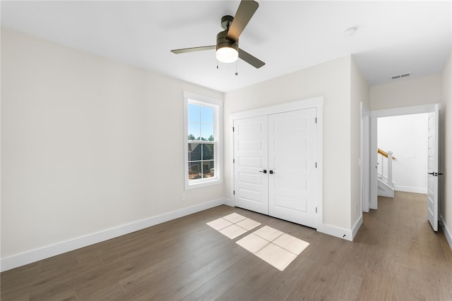 unfurnished bedroom with a closet, wood-type flooring, and ceiling fan