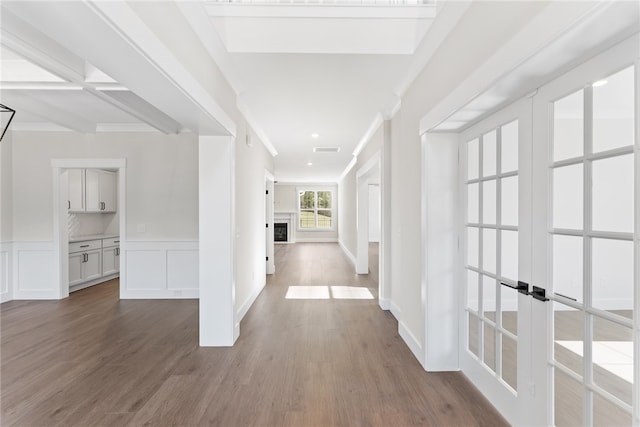 corridor with french doors, hardwood / wood-style floors, and beam ceiling