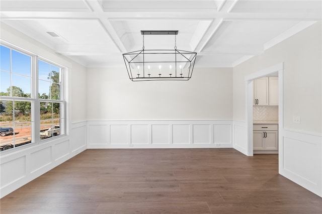 unfurnished dining area featuring a notable chandelier, ornamental molding, coffered ceiling, and dark hardwood / wood-style flooring