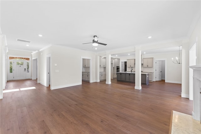 unfurnished living room with sink, crown molding, dark hardwood / wood-style flooring, and ceiling fan with notable chandelier