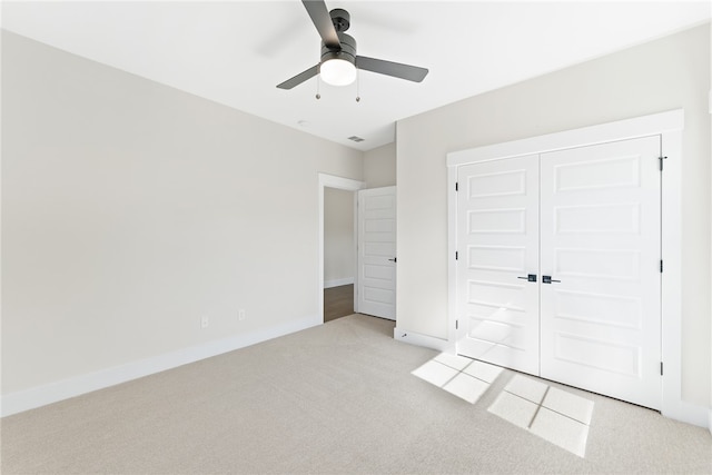 unfurnished bedroom featuring a closet, light colored carpet, and ceiling fan