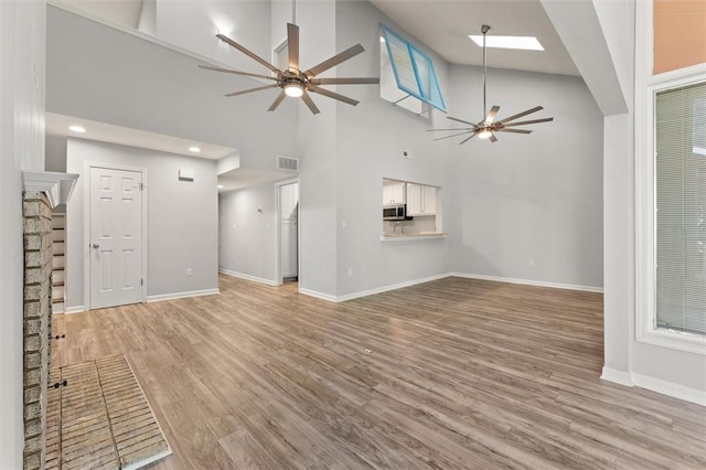 unfurnished living room with visible vents, a ceiling fan, baseboards, and light wood finished floors