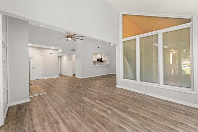 unfurnished living room featuring visible vents, wood finished floors, baseboards, ceiling fan, and high vaulted ceiling