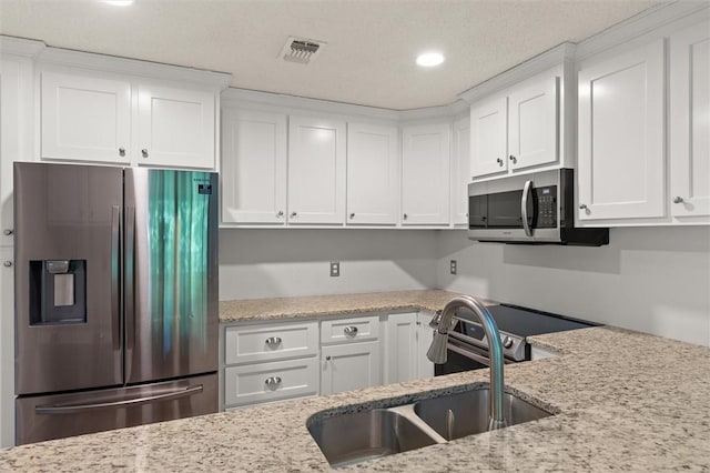 kitchen with a sink, appliances with stainless steel finishes, and white cabinets