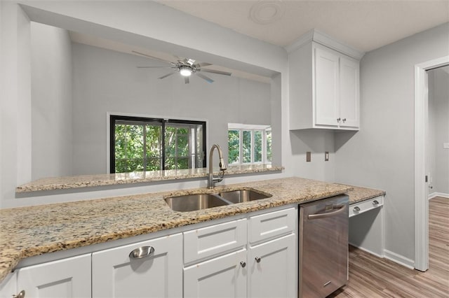 kitchen featuring baseboards, light wood-type flooring, white cabinets, a sink, and dishwasher