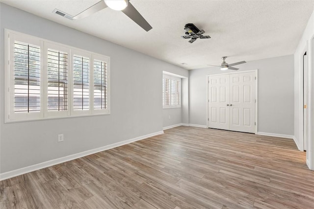 unfurnished bedroom featuring baseboards, visible vents, multiple windows, and light wood-style flooring
