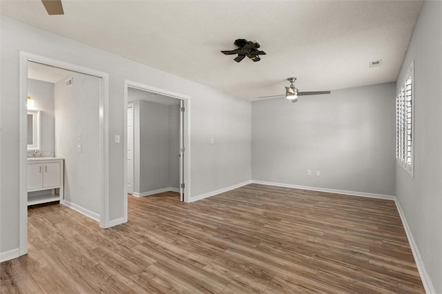 unfurnished bedroom with baseboards, ceiling fan, wood finished floors, and visible vents