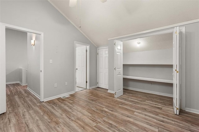 unfurnished bedroom featuring visible vents, baseboards, lofted ceiling, and wood finished floors